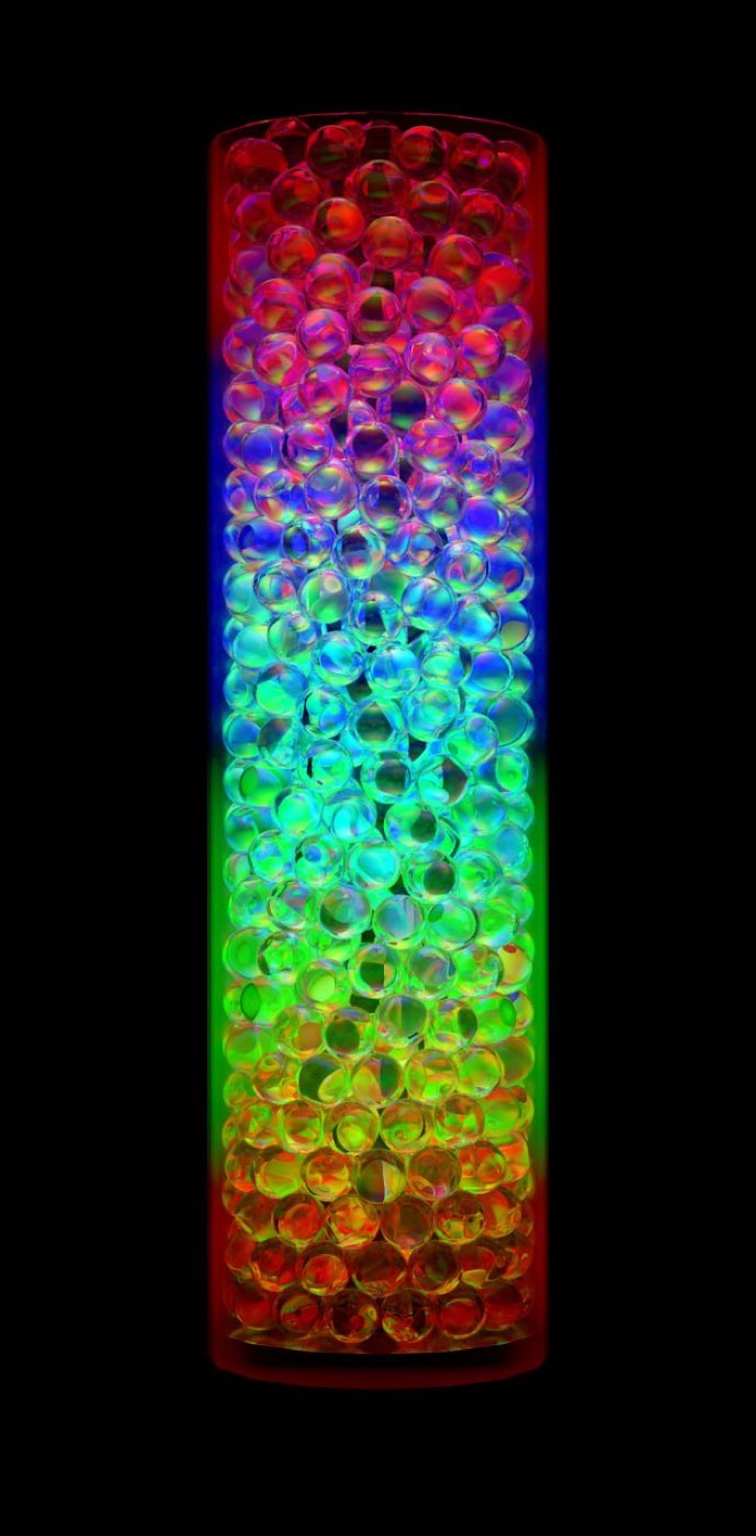 A render of clear marbles inside a tube, lit in a vertical gradient of red, blue, green and orange